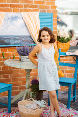 Cute child girl sits in outdoor cafe with oranges fruits. Provence.