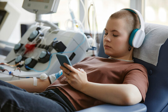 Woman using smart phone lying on couch and donating blood