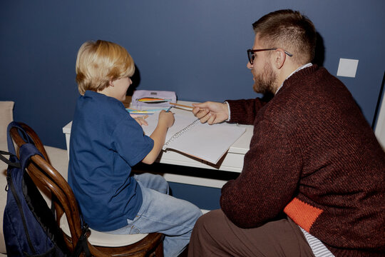 Father helping son with homework at a table indoors