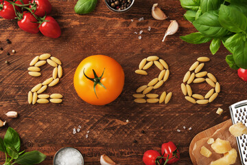 2026 figures with Italian ingredients on a rustic wooden background, tomatoes, pasta, basil and parmesan