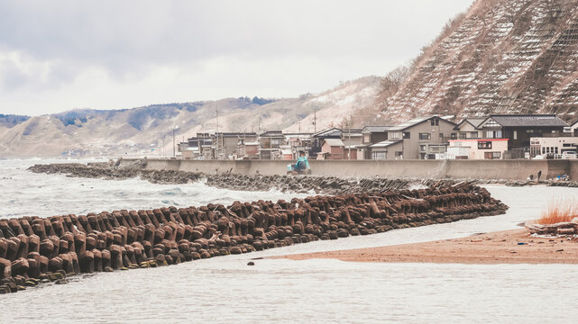 View of the rugged coastline meets the turbulent sea, where concrete barriers stand firm against crashing waves, Izumozaki, Niigata, Japan.
