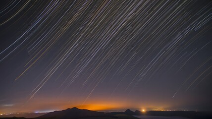 Star trails over distant landscape and city lights
