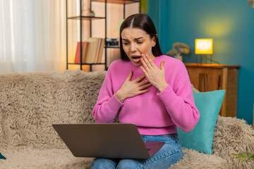 Young woman at home having video call sadly receiving unpleasant news, feeling emotionally disappointed. Caucasian sad girl on sofa reacting to bad message, expressing frustration and negative mood