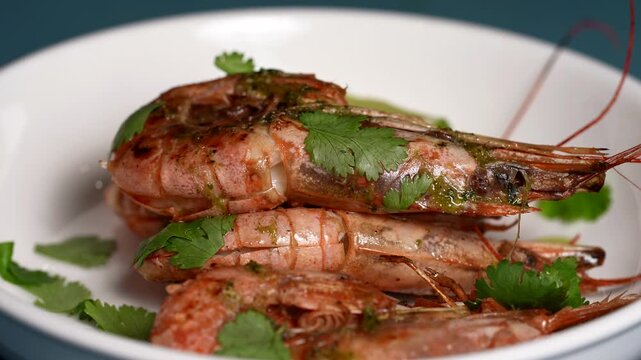 Close-up of grilled whole shrimp covered in green herb sauce, garnished with fresh cilantro leaves.