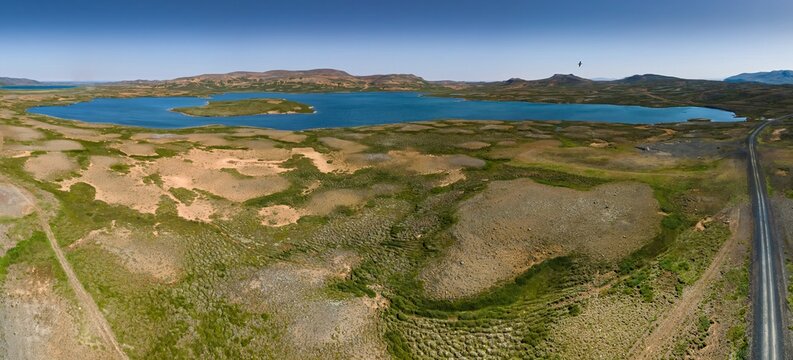 Aerial view of Hvilftarvatn lake's waters reflect the clear sky, contrasting with the earthy tones of the surrounding landscape, Raufarh&Atilde;&para;fn, Nor&Atilde;&deg;ur&Atilde;&frac34;ing, Iceland.