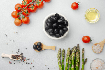 Bowl of black olives with tomatoes asparagus and cooking ingredients
