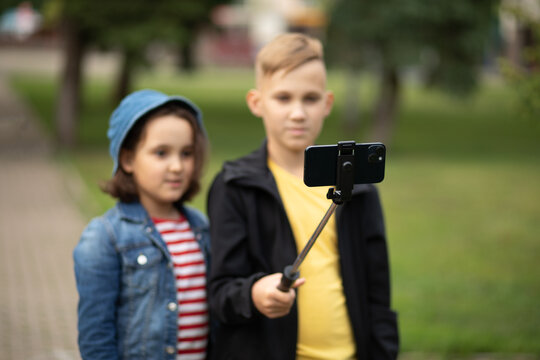 Girl and boy teenagers bloggers influencer records videos from the blog on a smartphone outdoor. Kids have fun with online live streaming for social network.