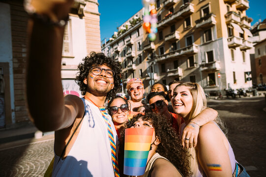 Smiling male and female friends taking selfie on street during sunny day