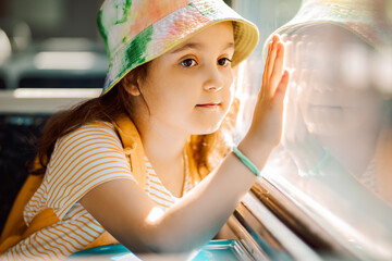 Little cute girl looking out train window outside while it moving. Travel, tourism, vacation and family concept.