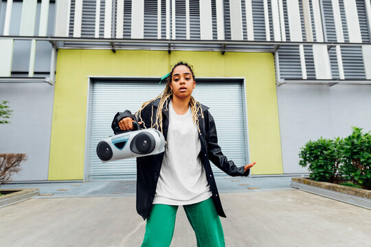 Young woman with boom box dancing in front of shutter