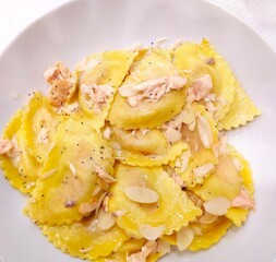 Salmon ravioli served with almonds and poppy seeds on a white plate, close-up. isolated.  Italian cuisine.