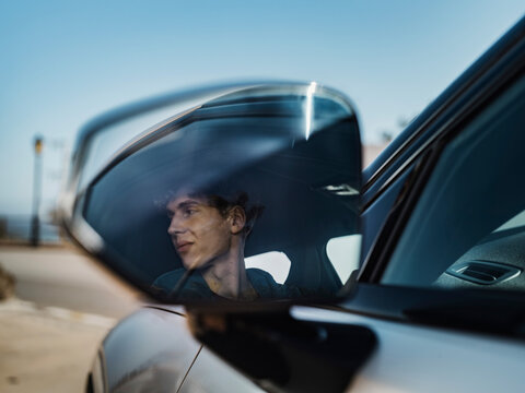 Reflection of man on side-view mirror of car