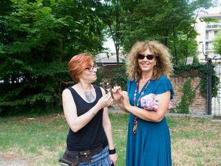 Fototapeta premium Two Adult Women Enjoying a Sunny Day Outdoors with a Shared Moment of Connection in a Garden Setting