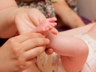 Massage doux des pieds d’un bébé lors d’une séance de bien-être, avec mains d’adulte en gros plan