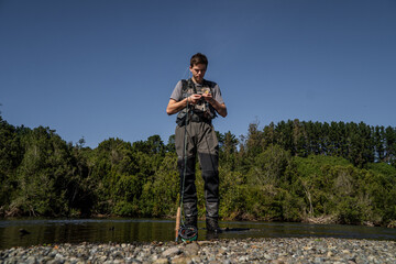 Young Fisherman Setting Up Rod Before Fly Fishing in River