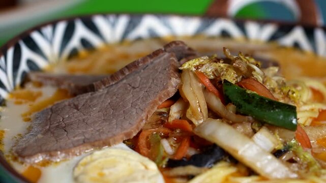Ramen topped with beef slices, stir-fried cabbage, carrots, and green peppers in savory broth.