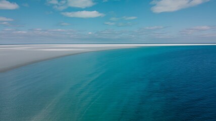 Vast turquoise ocean meeting a pale sandy shore under a blue sky