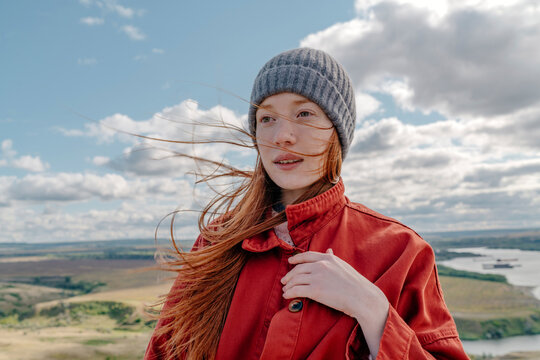 Young woman with knit hat standing under cloudy sky