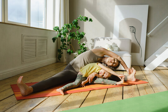 Mother and daughter practicing Parivrtta Janu Sirsasana pose at home