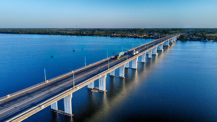 Aerial view of the bridge slicing through the dark blue waters, connecting distant shores under a clear sky, Kherson, Kherson Oblast, Ukraine.