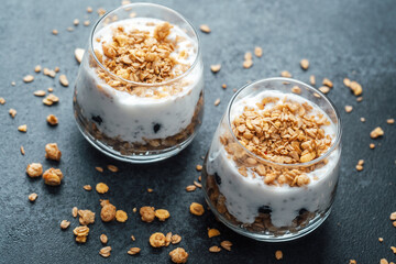 Parfaits with granola and yogurt in glass on dark  background