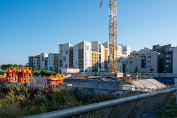 Concrete foundation site with residential buildings and cranes in background, emphasizing the construction phase of real estate projects and housing expansion in cities.