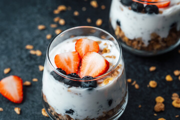 Yogurt granola parfait with strawberries and blueberries on  dark background