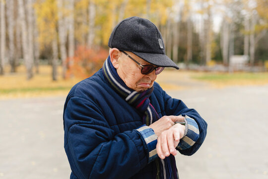 Elderly man checking time on wristwatch at park