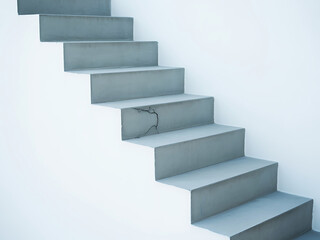 Modern concrete staircase ascending against a clean white wall