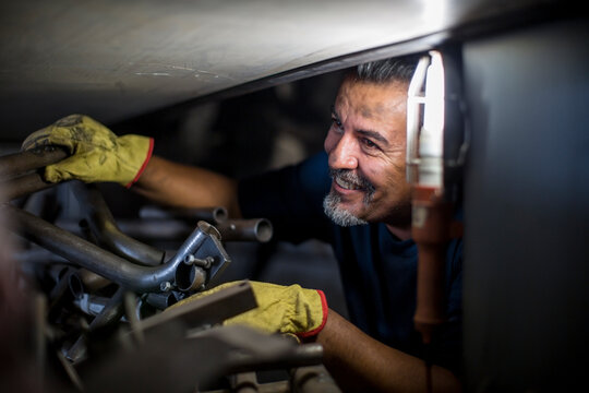 Smiling mechanic working on motorcycle in workshop