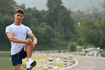 An Asian Athlete warming up outdoors, stretching legs to prevent injury before jogging, emphasizing...