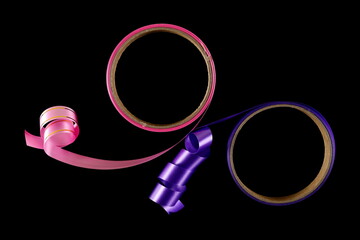 Violet and pink paper ribbon twisted with cardboard roll isolated on black background and texture	