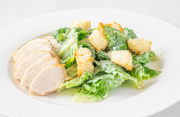 Classic Caesar salad topped with chicken breast served on clean white plate