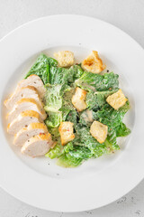 Classic Caesar salad topped with chicken breast served on clean white plate