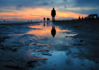 Silhouette of a person walking along a beach at sunset
