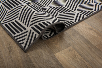 A specially designed carpet is folded on a wooden floor.