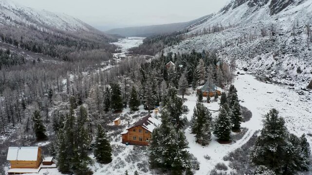 Aerial view of wooden houses nestled among snow-covered trees, creating a striking contrast against the stark white landscape, Aktau, Republic of Bashkortostan, Russia.