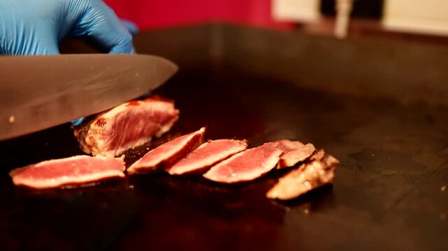 Freshly sliced, perfectly seared steak pieces lined up on the grill, glistening with juices.
