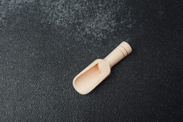Wooden scoop lying on a dark surface in a kitchen setting