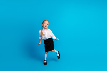 Cheerful Young Schoolgirl in Uniform Against a Blue Background Embarking on a Fun Learning Adventure at School