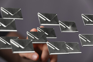 Abstract image of hand interacting with floating email icons, representing digital communication and inbox management.