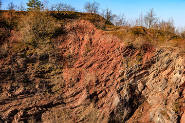 Rugged red rock formation with sparse trees under clear blue sky