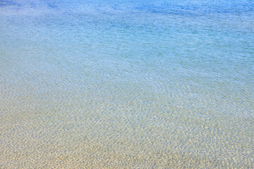Crystal clear shallow ocean waves glistening under the sun