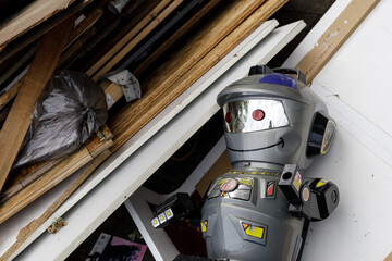 A discarded robot toy amidst construction debris.  Perfect for themes of waste, technology, or...