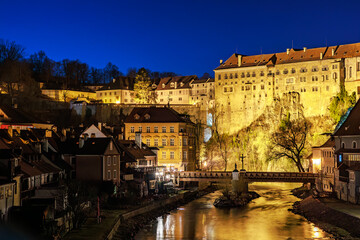 Obraz premium Historic castle above illuminated town at night with clear blue sky