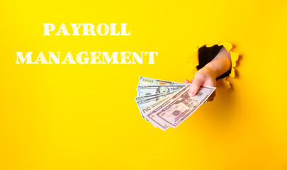 Hand holding cash through a hole in a bright yellow wall with payroll management text displayed