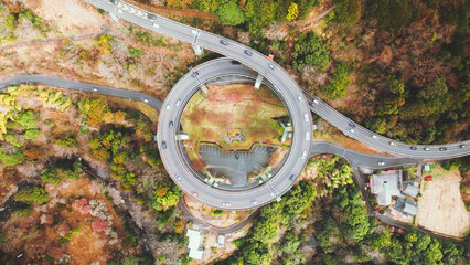 Aerial view of the Kawazu Nanadaru Loop Bridge, a concrete marvel spiraling amidst vibrant autumn foliage, creating a stunning contrast of man-made structure and nature, Kawazu, Shizuoka, Japan.