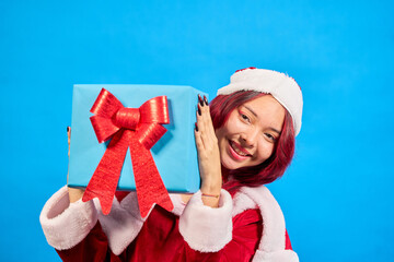 Smiling woman holding christmas gift on blue background
