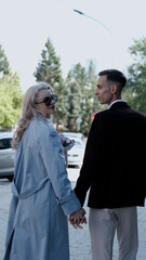 A bride and groom in love walking along a city street in summer