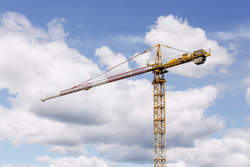Construction crane against sky. Tower crane on building site. Industrial machinery on blue sky...